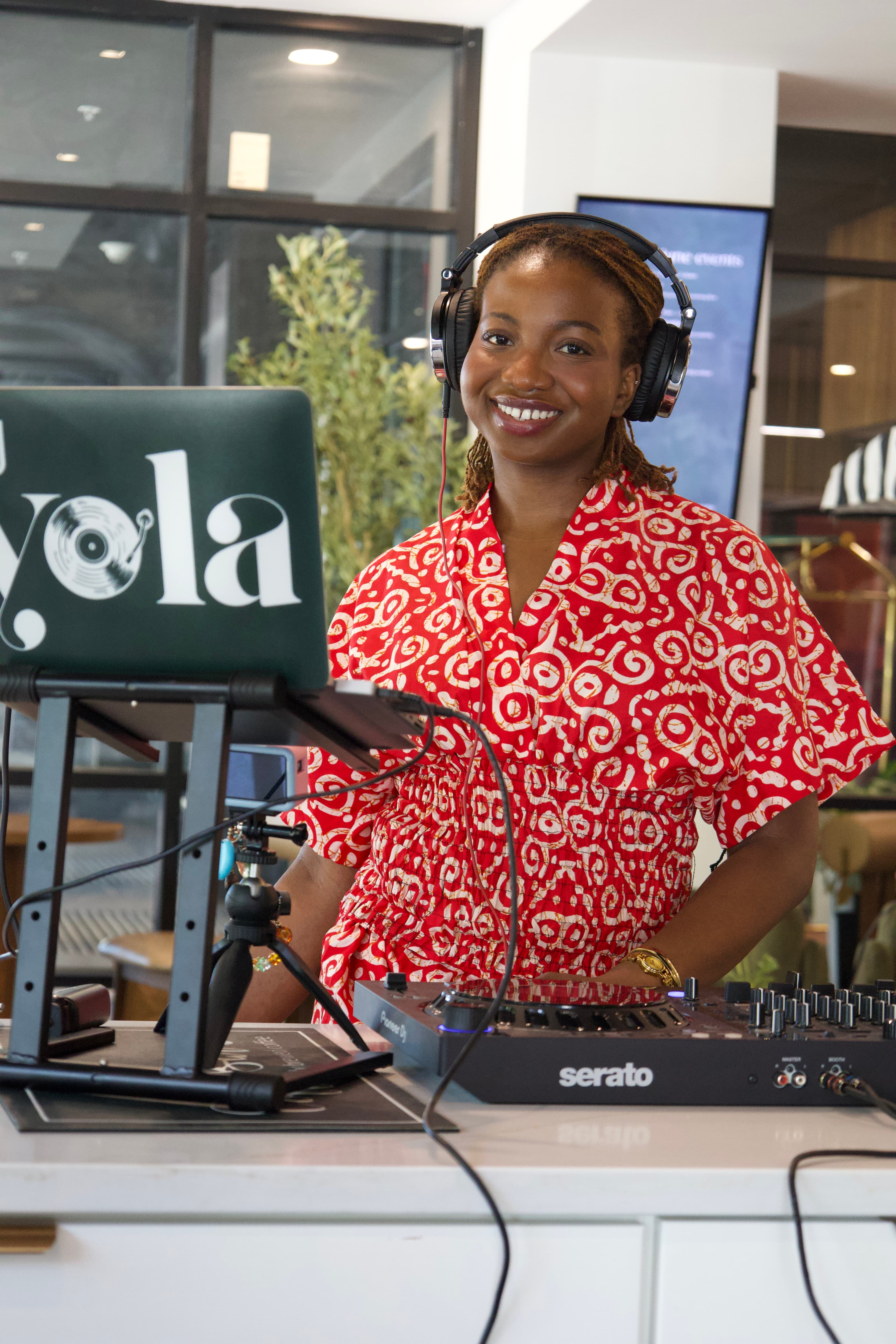 DJ smiling behind a turntable setup at a community event, photographed by ShuhraBilNoor