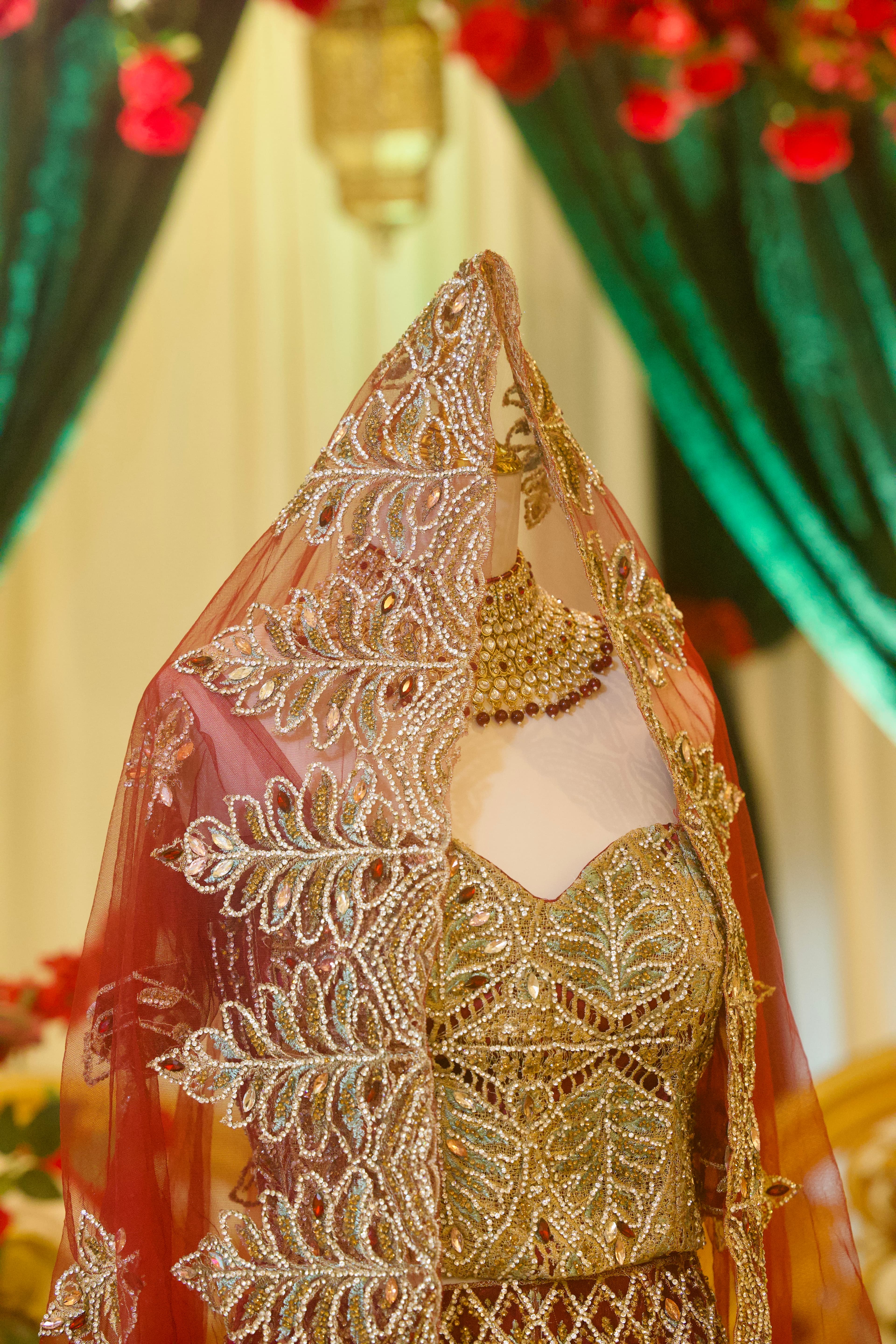 Close-up of a gold-embroidered bridal lehenga, veil, and jewelry, photographed by ShuhraBilNoor